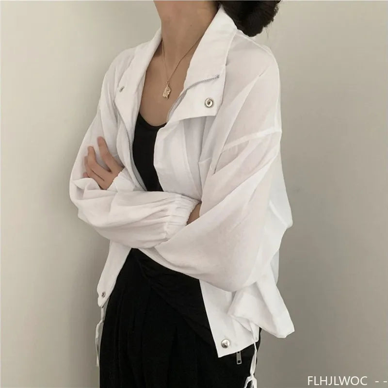 Person wearing a white shirt over a black top against a plain background