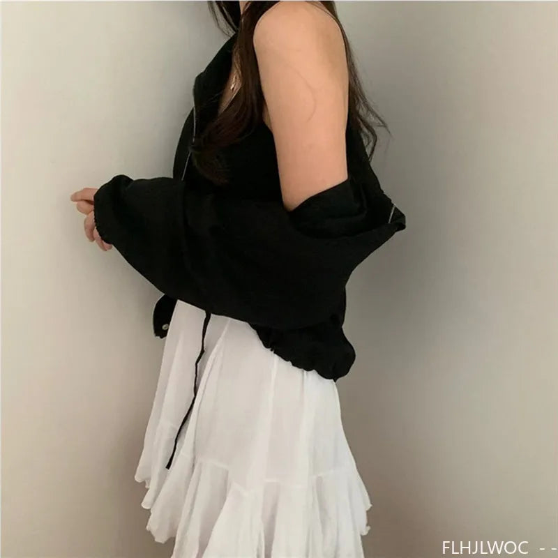 Person wearing a black jacket over a white dress against a plain background