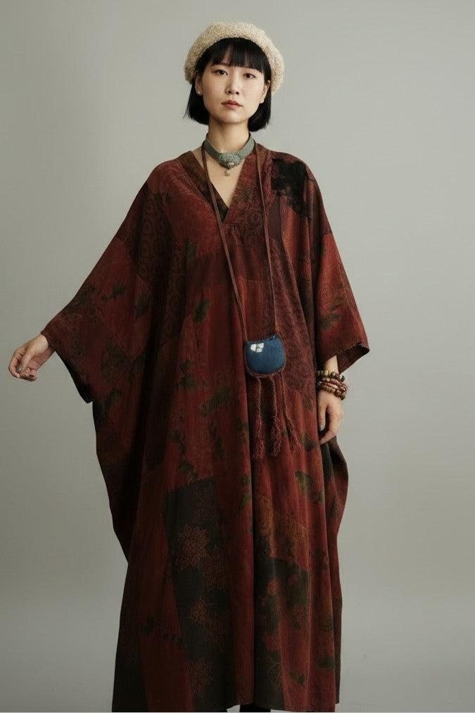 A model wearing a dark reddish-brown patterned kimono-style robe with wide sleeves, a beige beret, and a small blue crossbody bag, photographed against a neutral gray studio background.