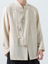 A person wearing a light beige linen-style long-sleeve jacket with a mandarin collar, front button closures, and a subtle green bamboo embroidery on the chest, paired with black pants against a light gray background.