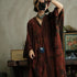 Person wearing a patterned dress holding a camera, with a blurred indoor background
