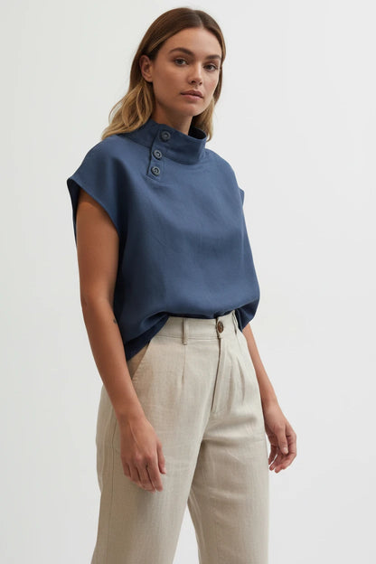 Person wearing a navy blue top and beige pants against a white background