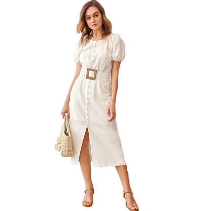 Woman wearing a white dress with a belt, holding a woven bag on a white background