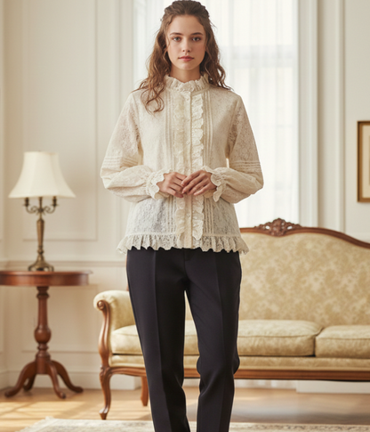 Woman wearing a white lace blouse and black pants in an elegant room.