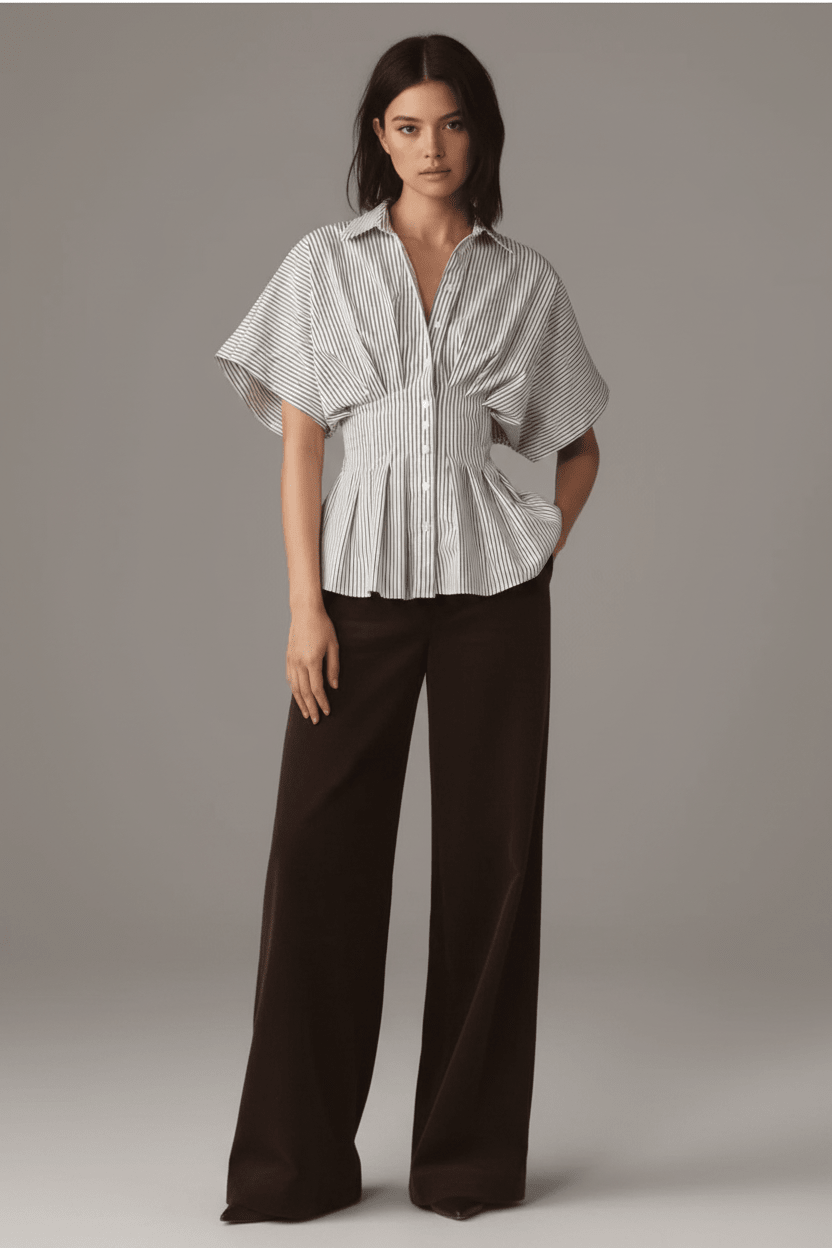 Woman wearing a checkered blouse and black pants against a plain background