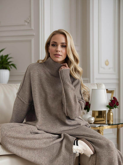 A woman wearing a brown turtleneck sweater and pants in a stylish room.