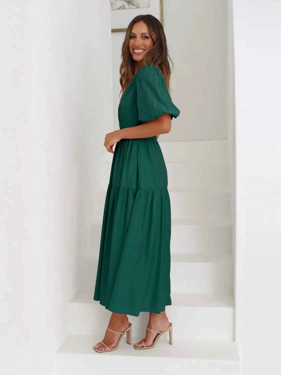 Woman in a green tiered midi dress with short puff sleeves and a surplice V-neck.