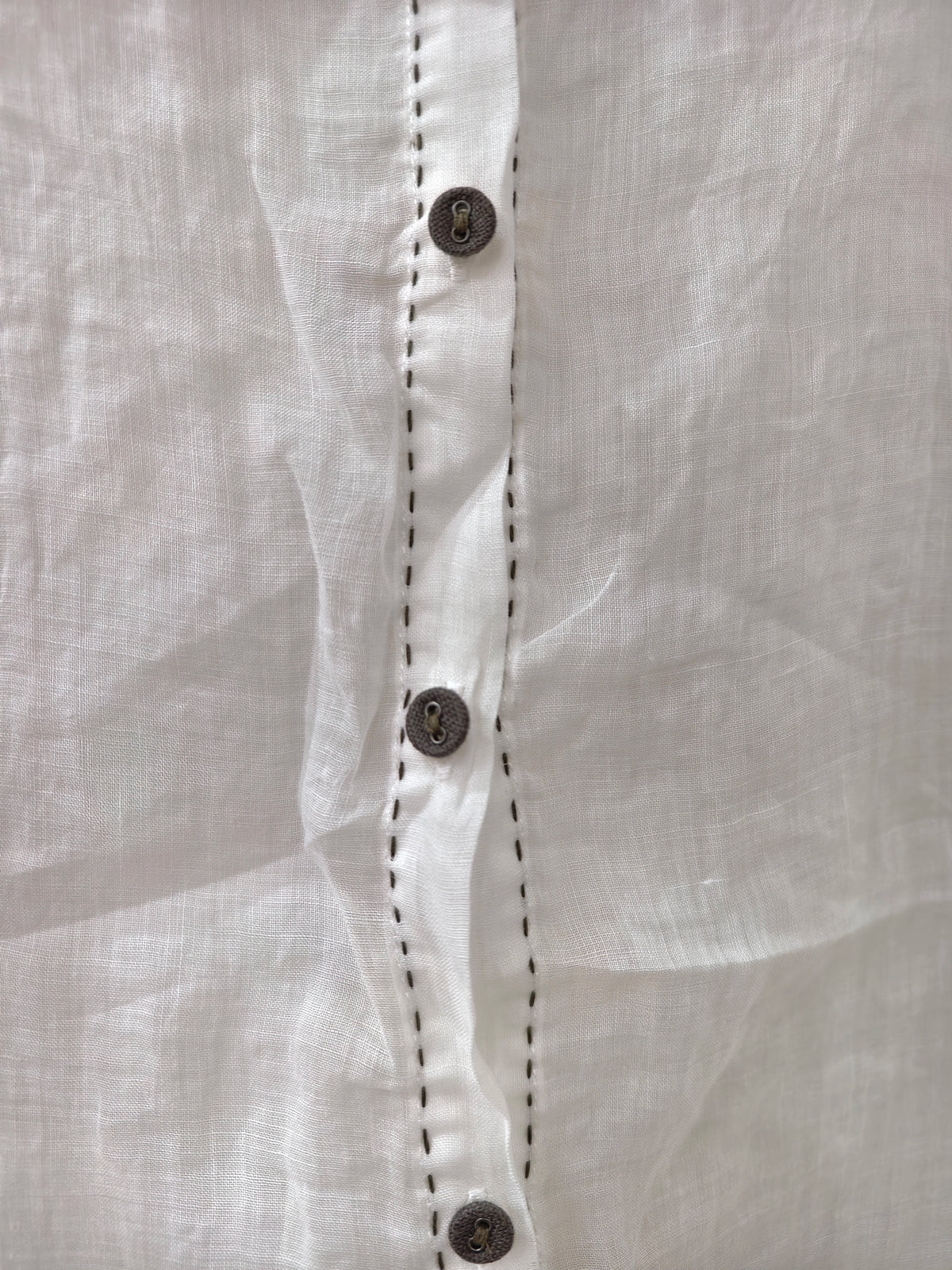 a button placket, paired with a dark skirt, photographed in a dim indoor setting.