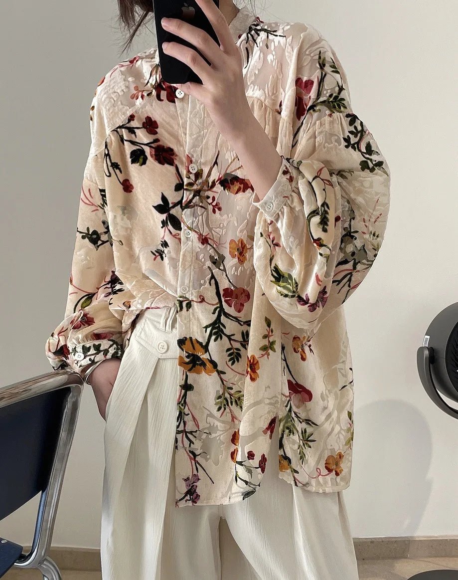Person wearing a floral blouse and white pants in an indoor setting.