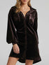 Brown velvet dress worn by a model on a gray background