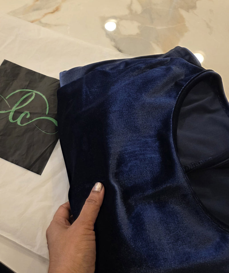 Blue fabric with a hand holding it, on a marble surface with a black bag in the corner.
