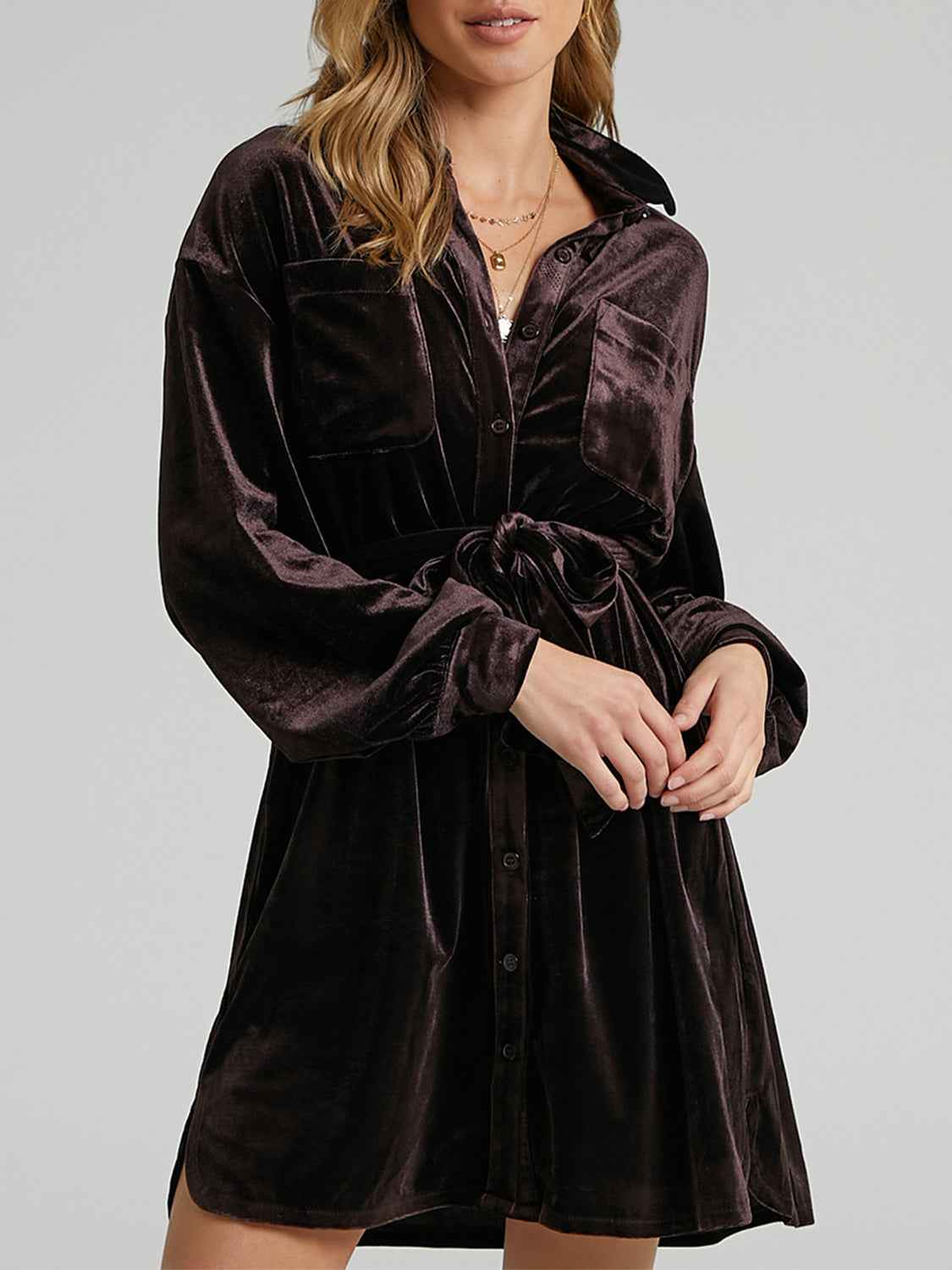 Woman wearing a brown velvet dress against a plain background
