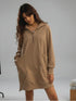 Woman wearing a beige hoodie dress against a plain background