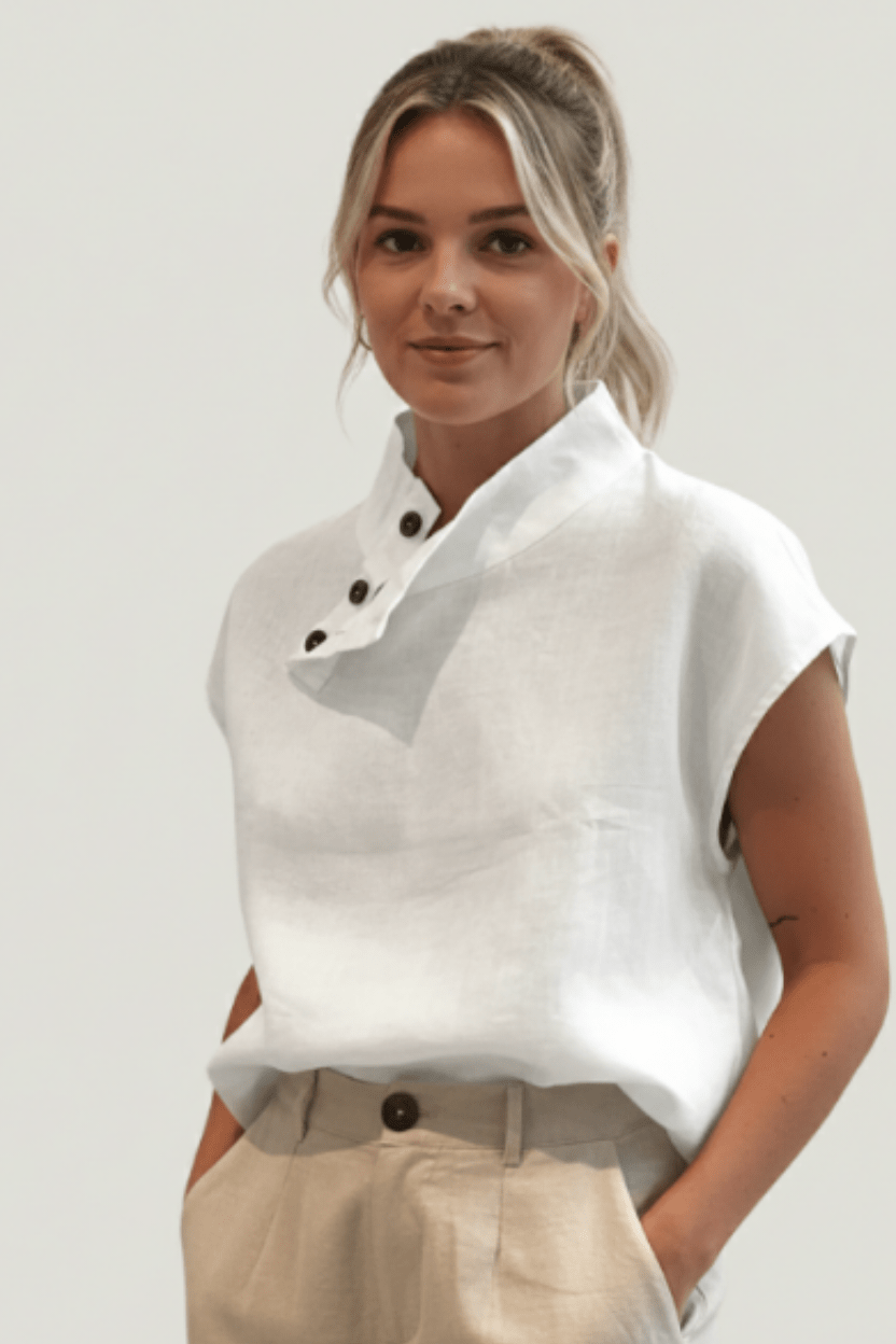 Woman wearing a white sleeveless top with a gray accent and beige pants on a plain background