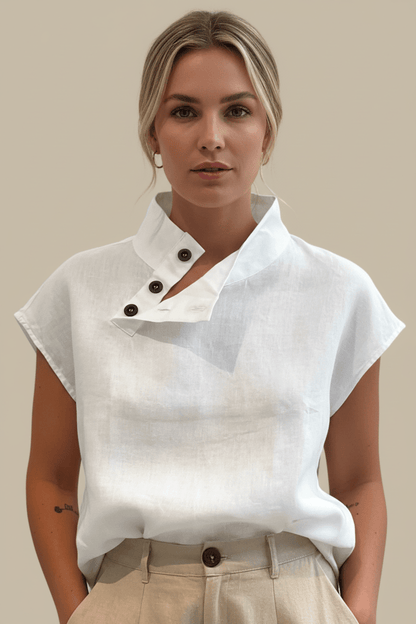 Woman wearing a white blouse with black buttons against a beige background