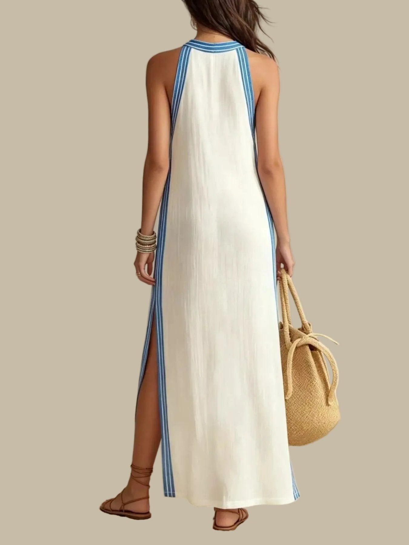 A woman modeling a sleeveless white maxi dress with blue side stripes and a blue-trimmed neckline, holding a woven straw bucket bag against a plain light background.