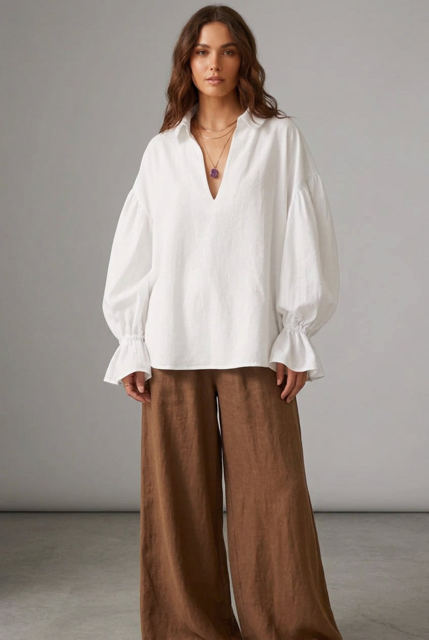 White blouse with ruffled sleeves worn by a person against a neutral background