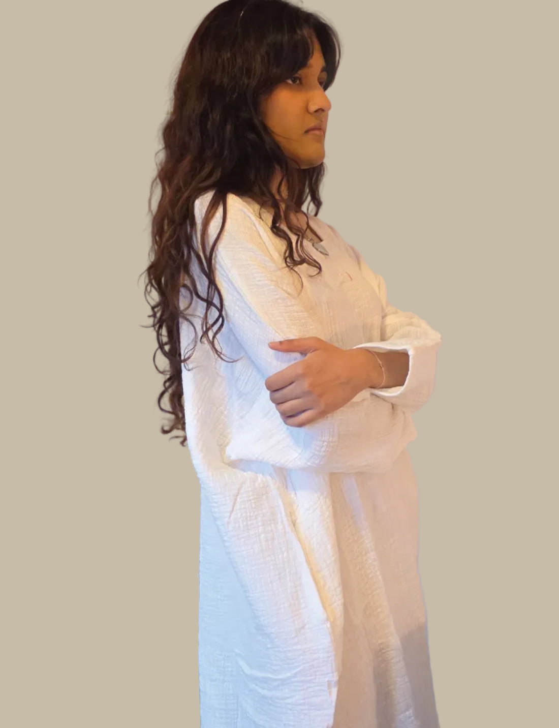 Woman in a white dress standing in a room with a mirror and door.